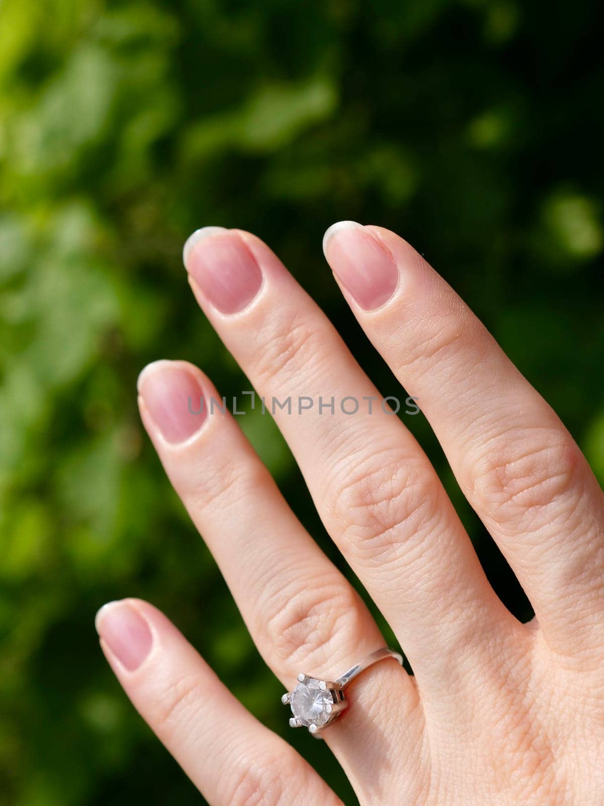 Japanese hygienic manicure on the female hand of the bride with a wedding ring. Clean and safe manicure. Beautiful fingers and nails without gel polish. Vertical