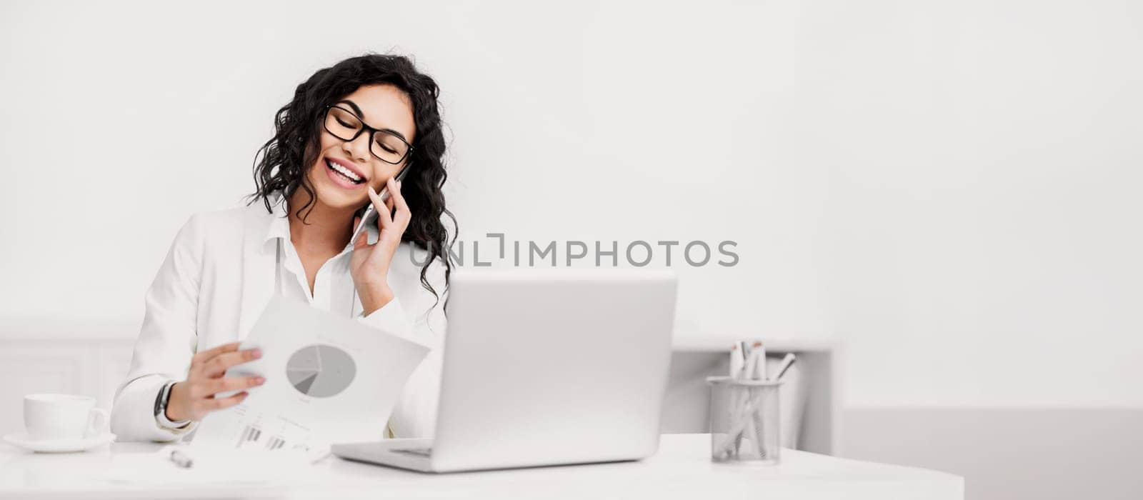Business, Technology And Communication Concept. Mexican woman making phone call while looking at document with graphs