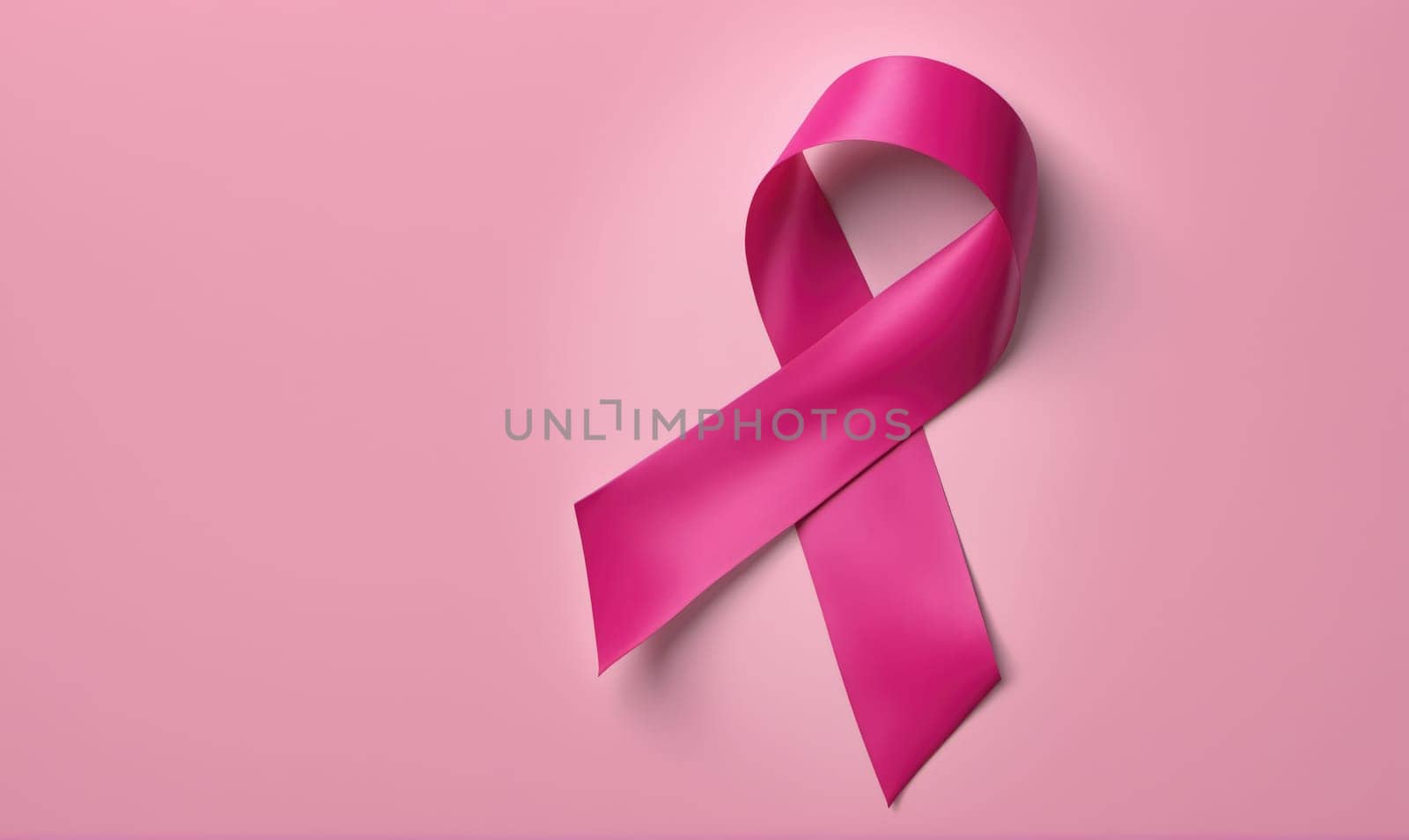 A pink ribbon is tied in a bow shape against a solid pink backdrop.