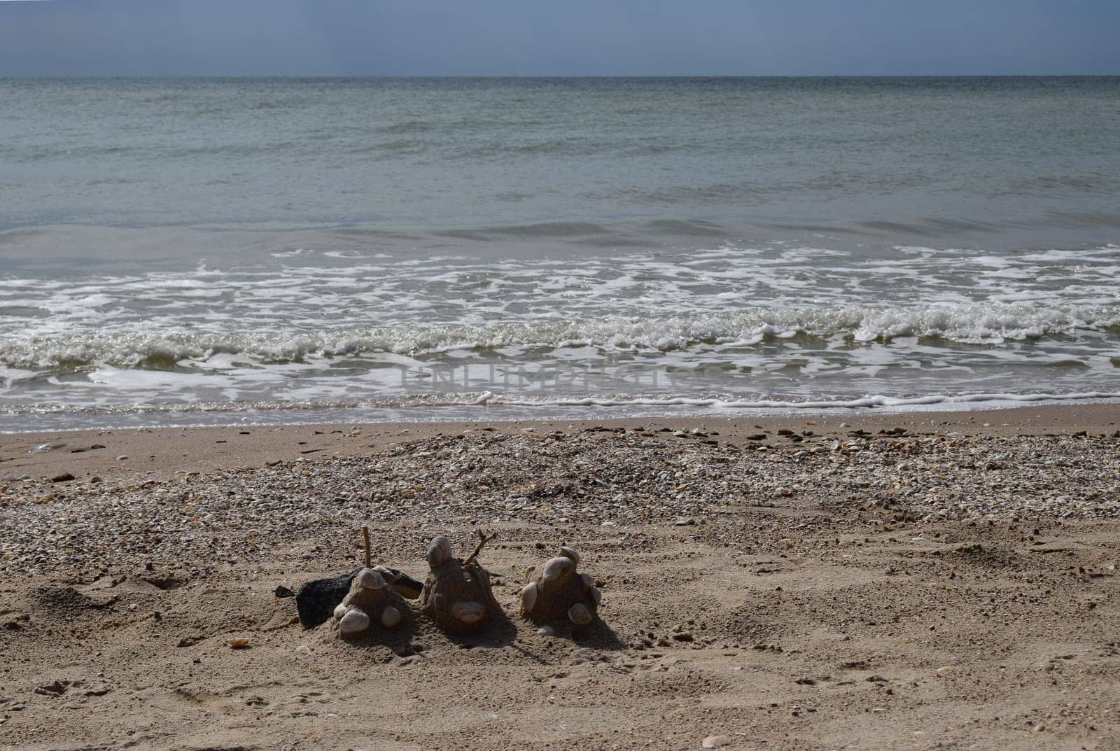 Sand castle with shells built on summer tropical beach. Close up of spade and shells on a beach.
