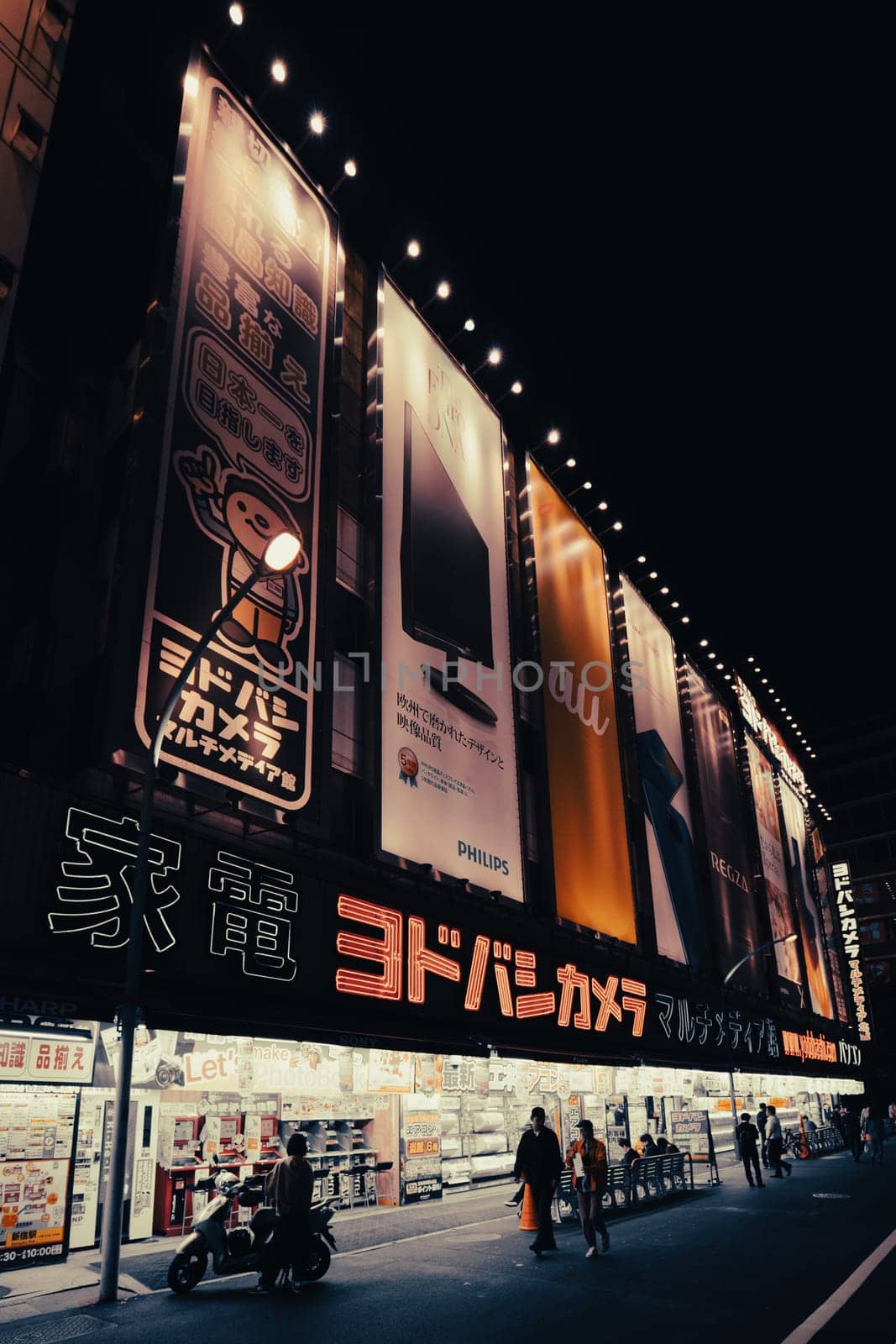 TOKYO, JAPAN - MAY 12 2019: Neon signs illuminate Tokyo’s busy Shinjuku neighborhood at night around Yodobashi camera store