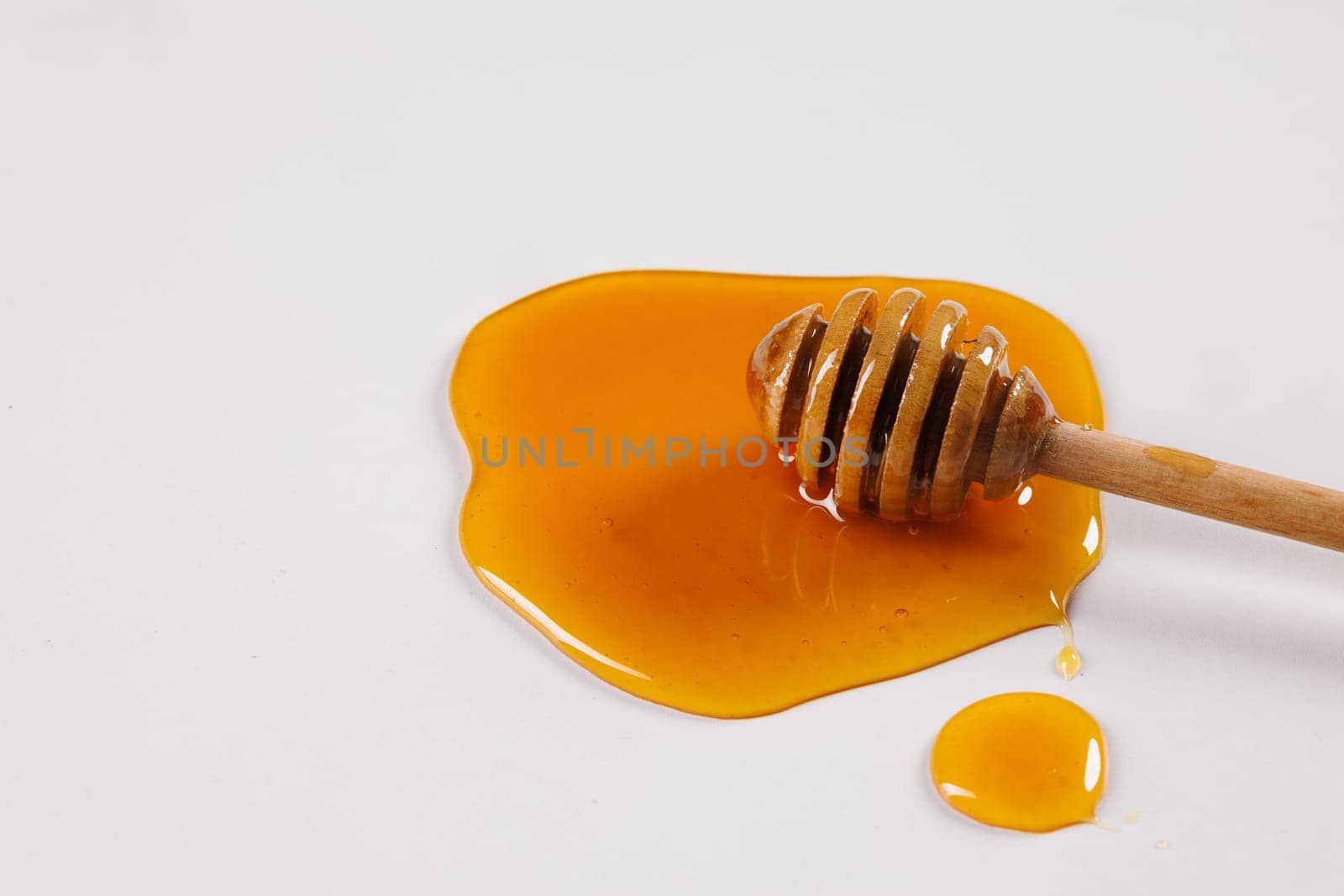 honey spoon with spilled honey on white background, top view, honey benefits concept