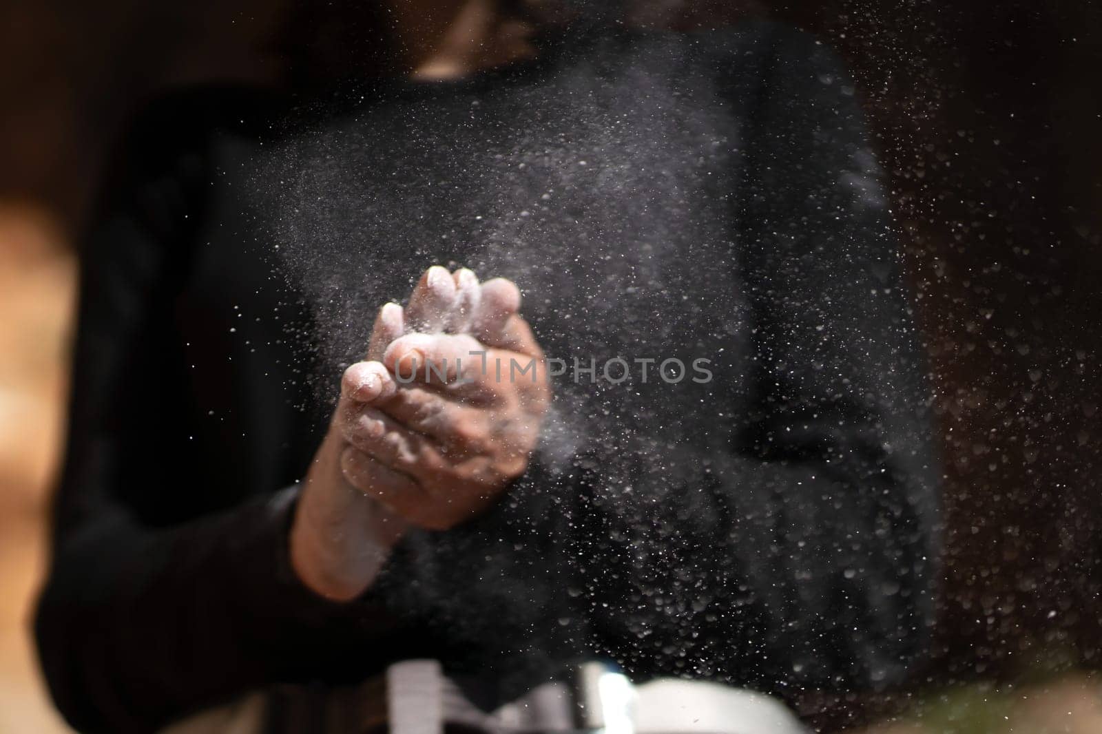 The girl is engaged in rock climbing, uses white powder of magnesia, claps her hands close-up, the woman leads an active lifestyle, climbs the mountains outdoor.