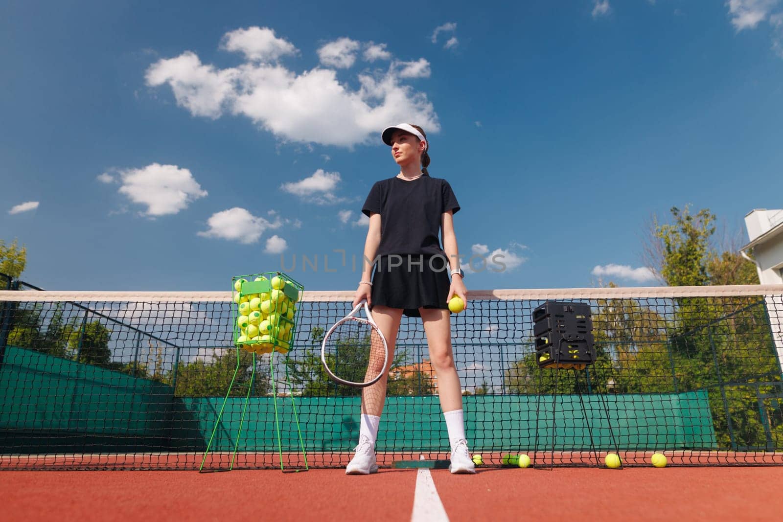 girl tennis player standing on tennis court holding racket and ball against net background preparing for tennis match