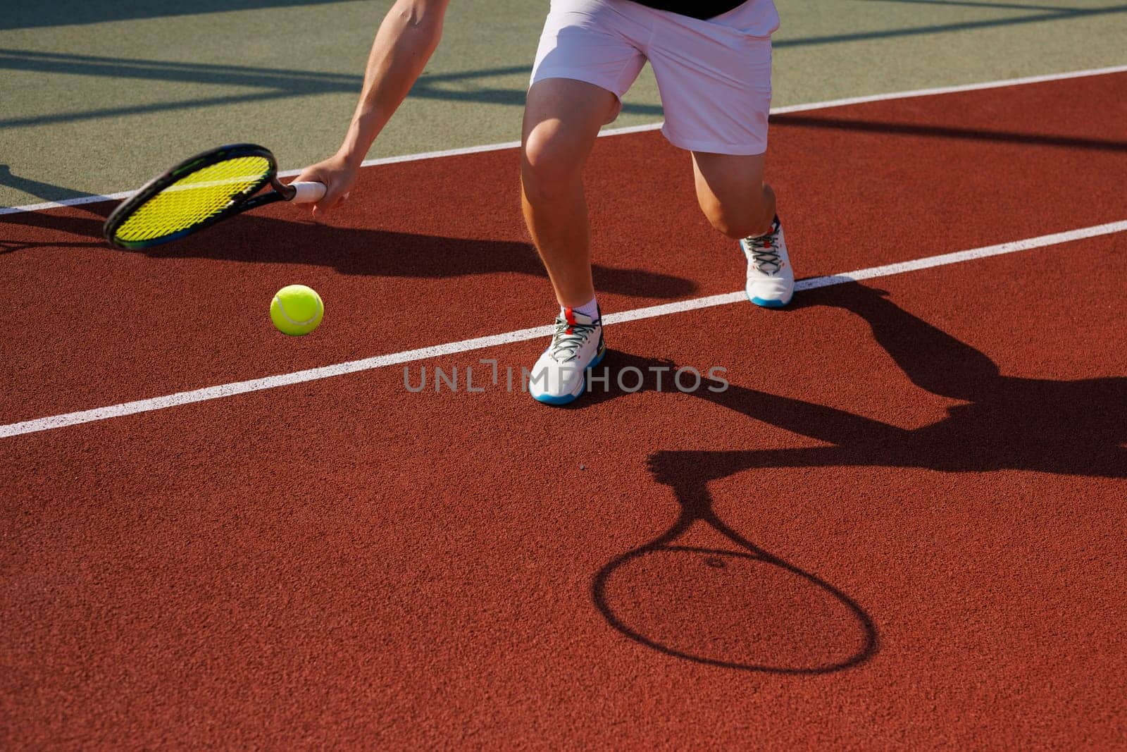 male tennis player hitting difficult ball close-up on tennis court background, creative concept tennis game,