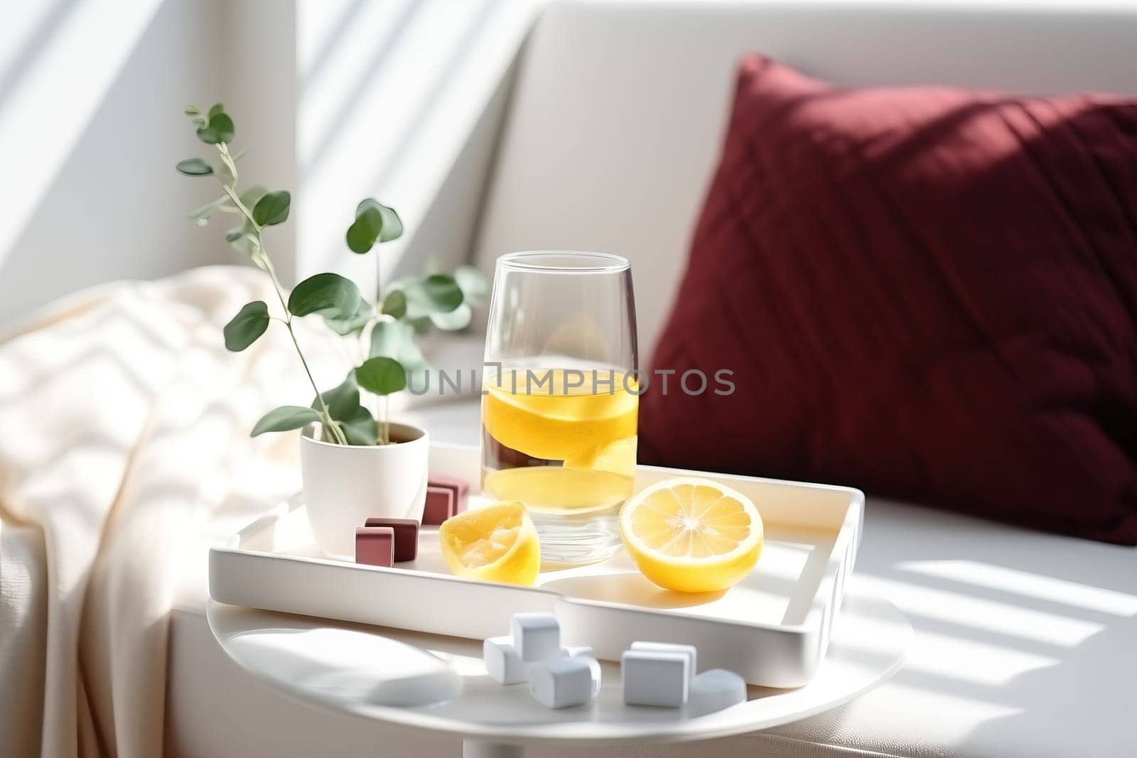 Refreshing drink with lemon slices on a tray, accompanied by a potted plant and colorful sweets, creating a cozy atmosphere.