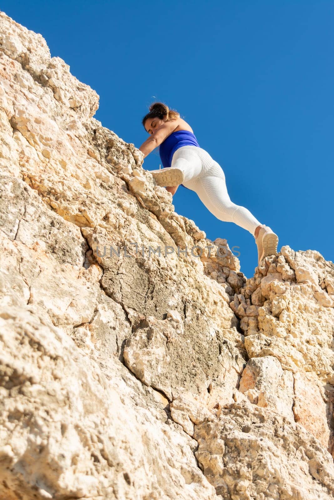 Woman climbing a rocky cliff in bright sunny weather, close to the summit, Latin woman, middle-aged, outdoors, climbing psicobloc in mallorca, balearic islands, spain,