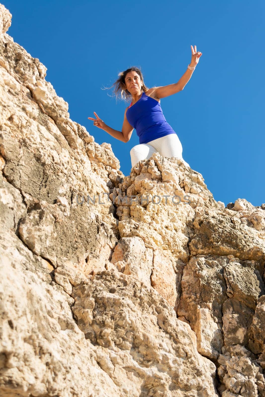 Woman standing on the summit of rocks with arms raised in victory, Latin woman, middle-aged, outdoors, climbing psicobloc in mallorca, balearic islands, spain,