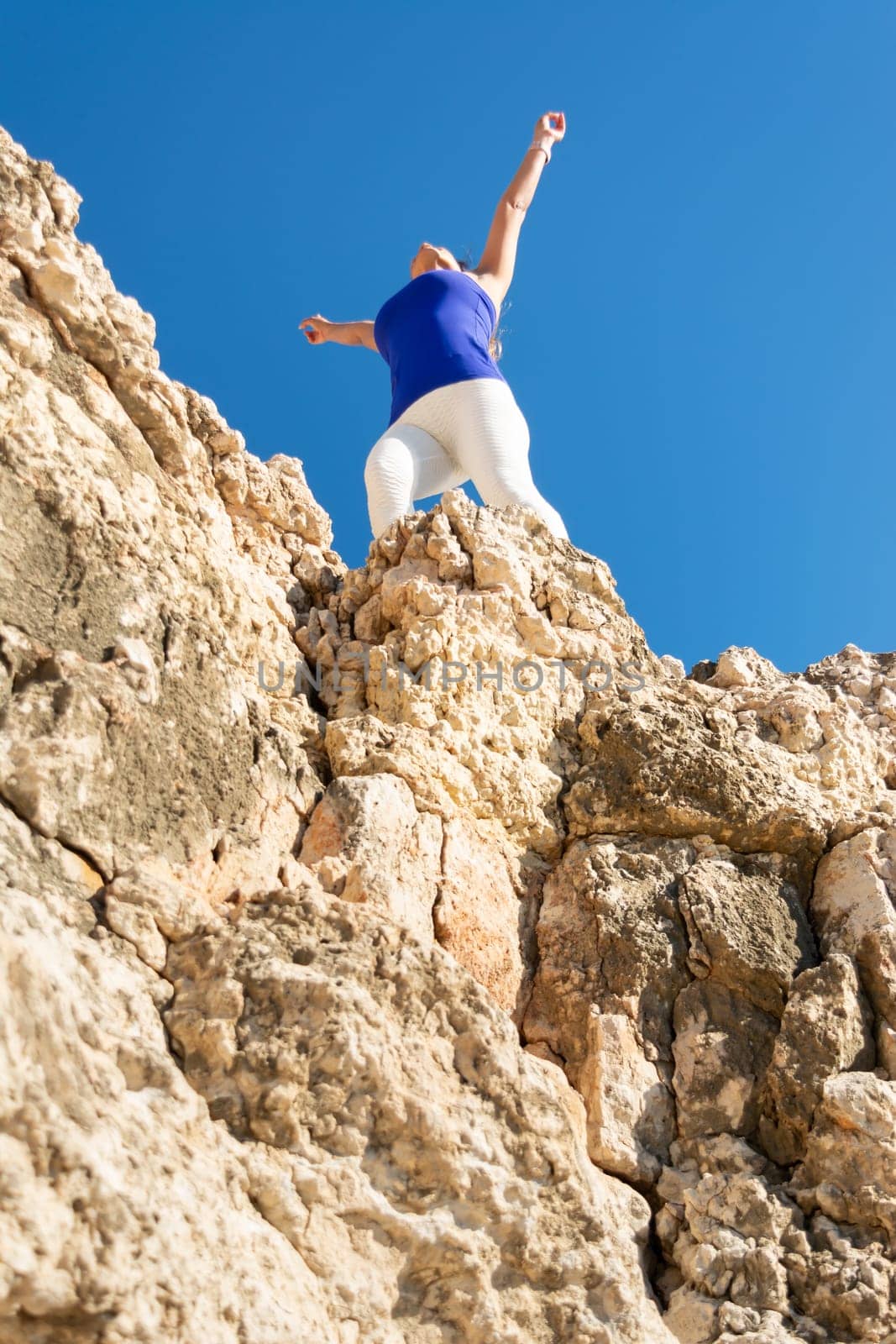 Woman standing triumphantly on top of rocky terrain, arms raised, Latin woman, middle-aged, outdoors, climbing psicobloc in mallorca, balearic islands, spain,