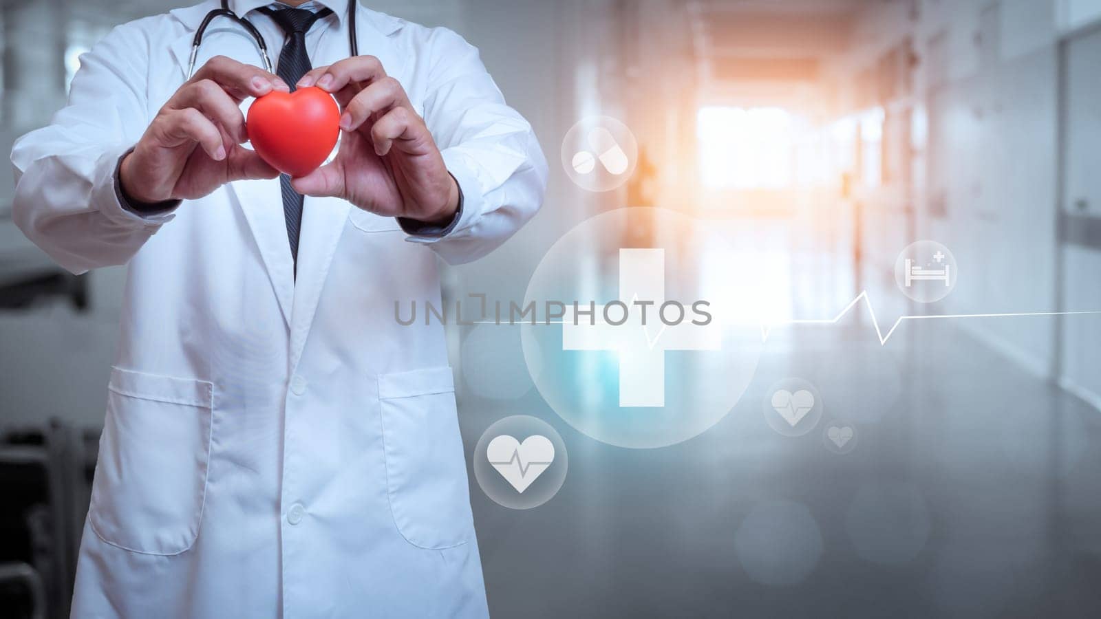 Doctor in lab coat holding red heart on hospital interior background