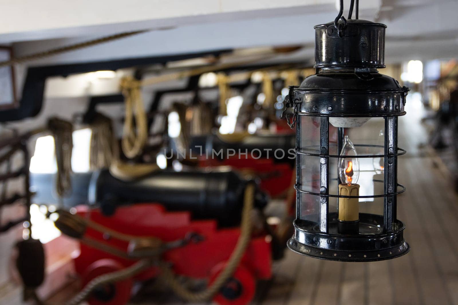 Historirical retro metal flashlight in front of cannon on battle sailing vessel - stand on deck