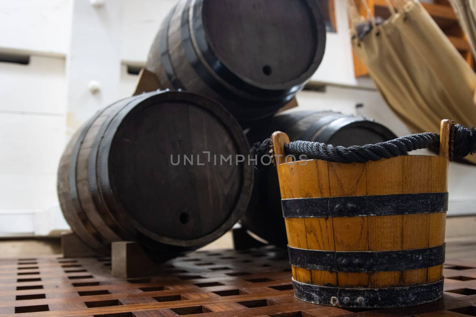 Wooden bucket near powder barrels in storage room on the battle vessell, sail ship