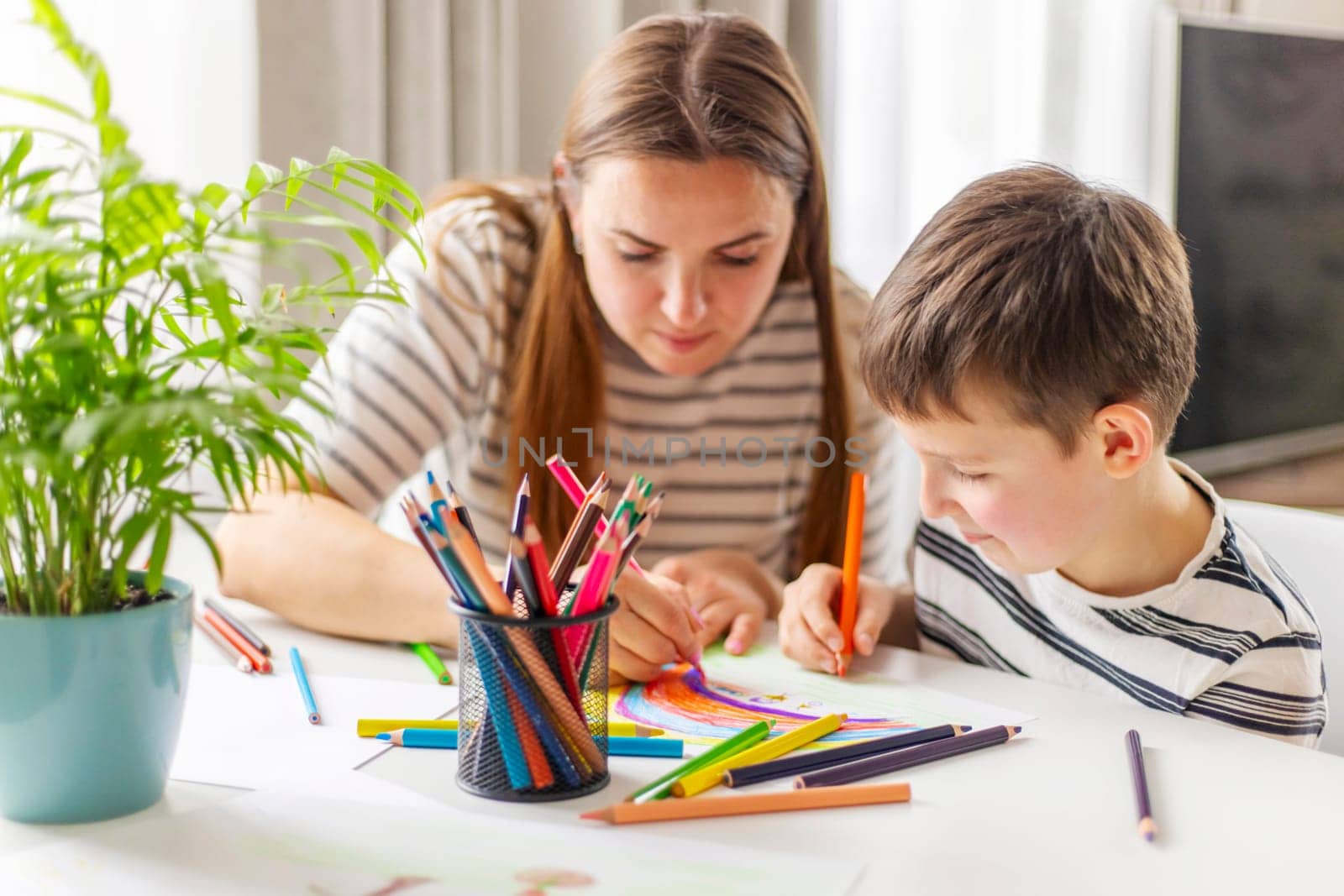 Happy family concept. Mother and her son drawing together. An adult woman helps a boy paint.