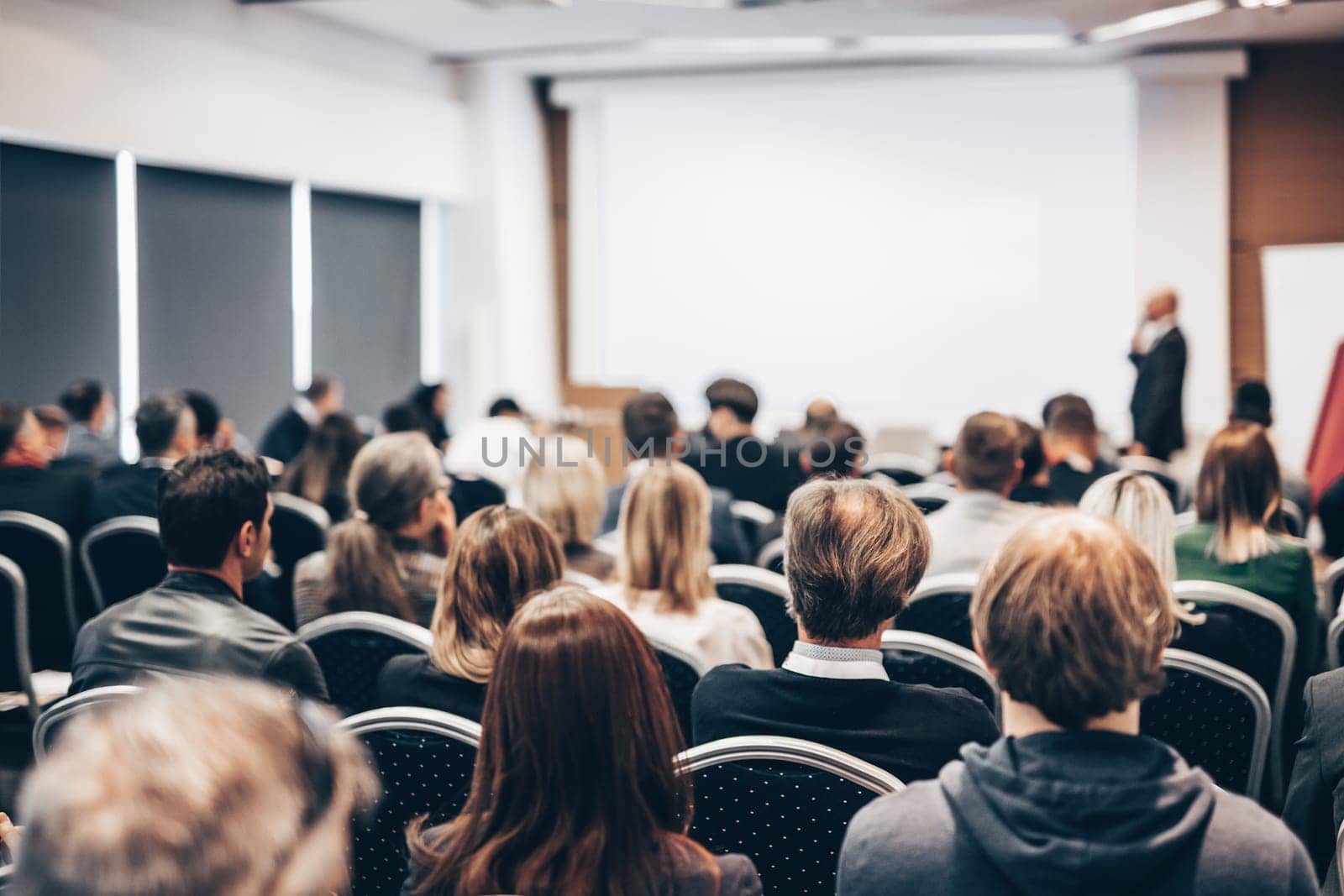 Speaker giving a talk in conference hall at business event. Rear view of unrecognizable people in audience at the conference hall. Business and entrepreneurship concept. by kasto