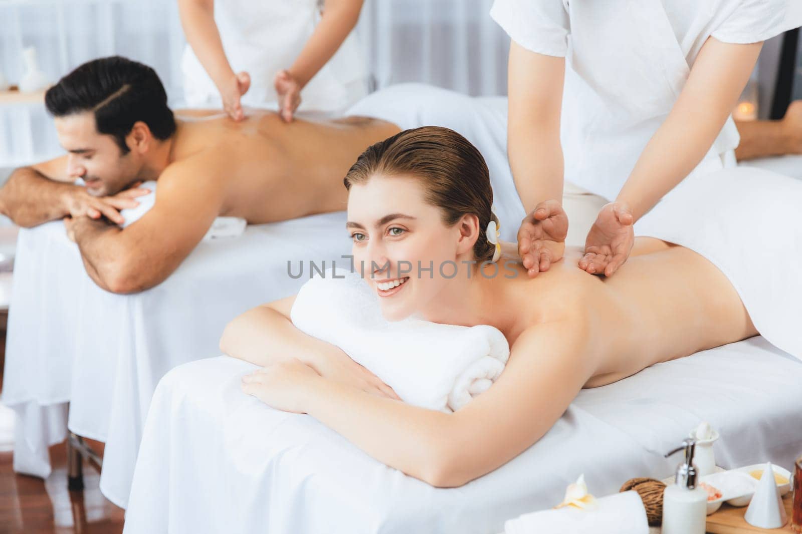 Caucasian couple customer enjoying relaxing anti-stress spa massage and pampering with beauty skin recreation leisure in day light ambient salon spa at luxury resort or hotel. Quiescent