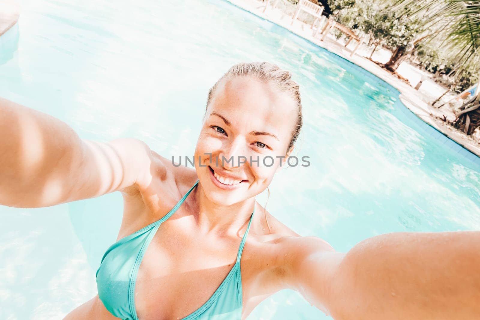 Lady taking a selfie at resorts poolside on summer vacations. Holidays and vacations.