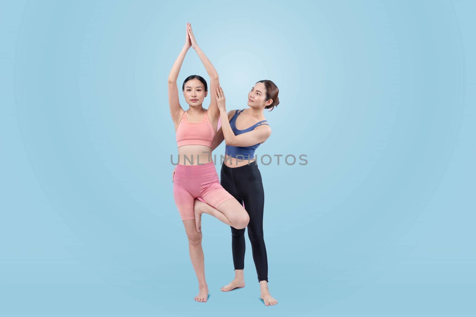 Asian woman in sportswear doing yoga exercise posing with trainer. Vigorous by biancoblue