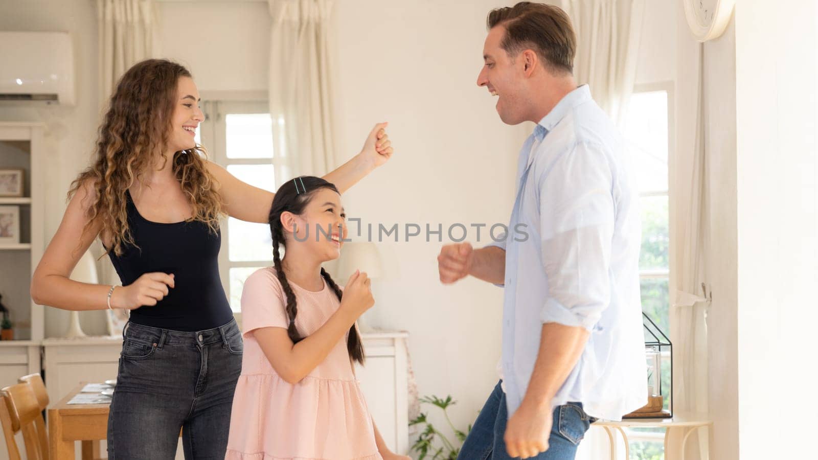 Happy family portrait with lovely little girl smile and looking at camera, lovely and cheerful parent and their daughter sitting together in living room at home with warm daylight. Panorama Synchronos