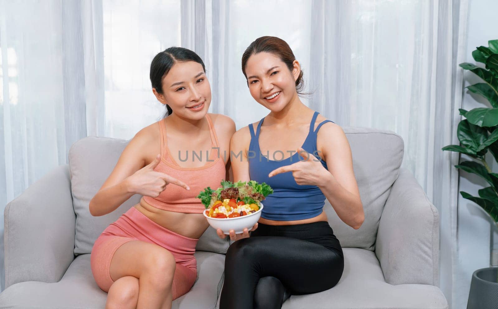 Young sporty Asian women in sportswear holding salad bowl together. Vigorous by biancoblue