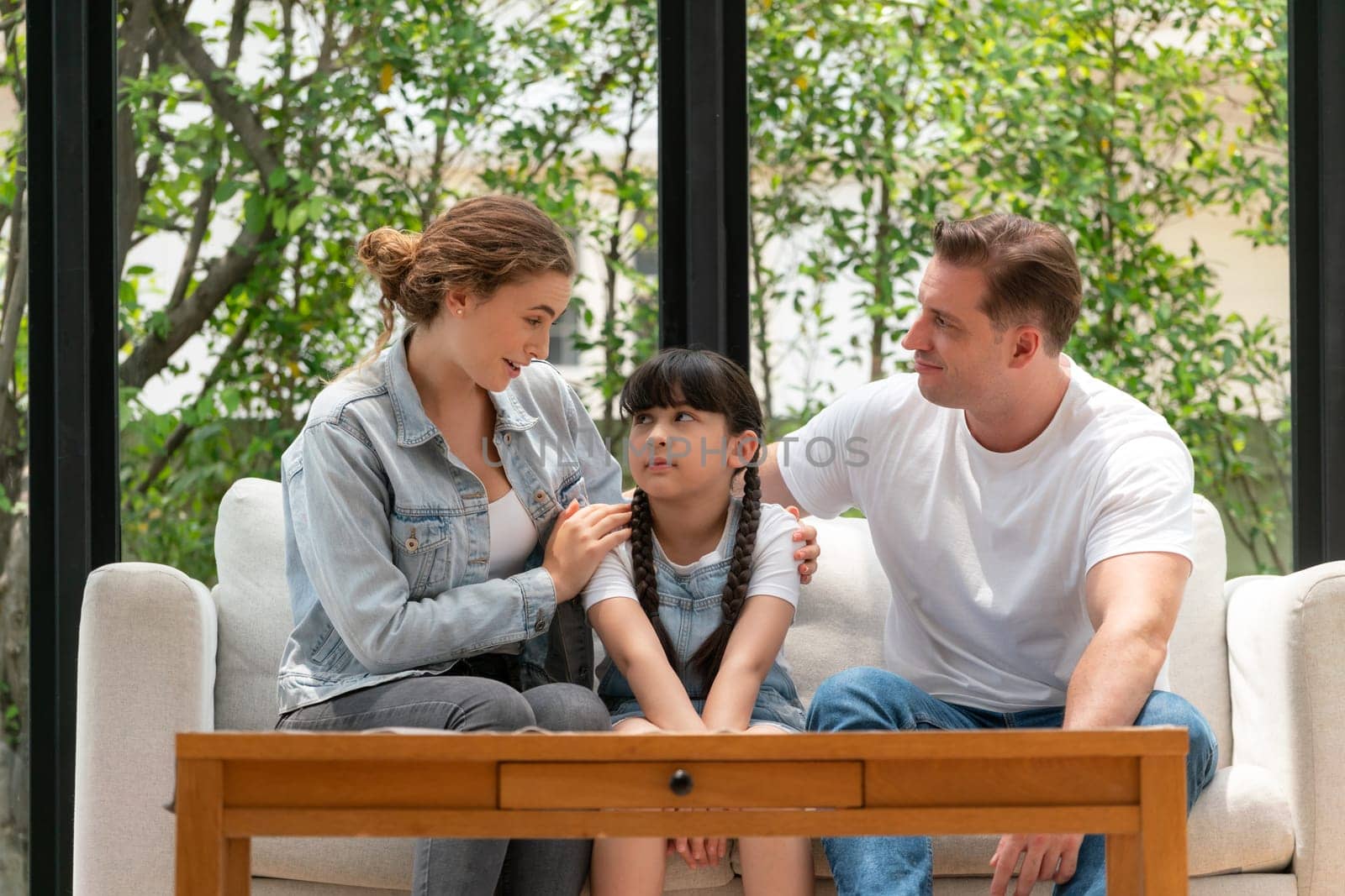 Parents comforting their daughter with loving hug, helping her feel secure and protected from fear, rest her head on shoulder. Happy family love and child care support concept. Synchronos