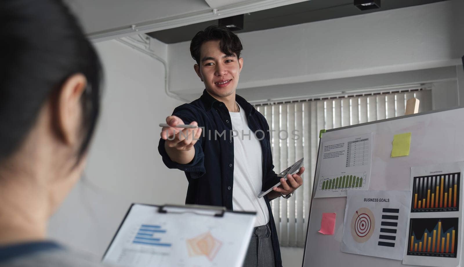 Young businessman explains work plan in meeting to teammates in conference room. by wichayada