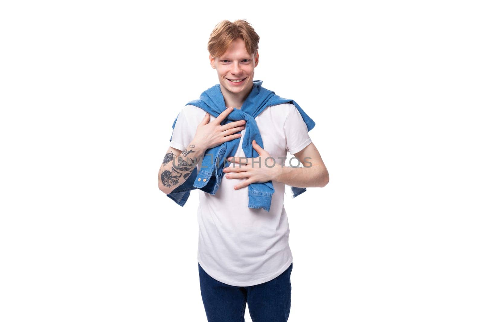 young handsome caucasian man with golden red hair with a tattoo on his arms is dressed in a white t-shirt.