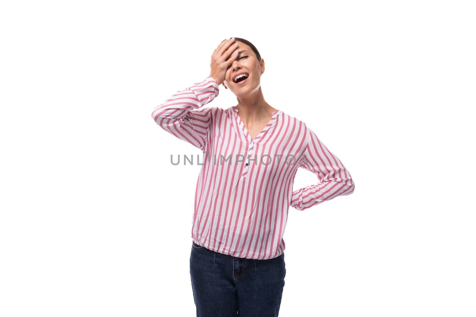 young european woman with black hair pulled back in a ponytail wearing a striped blouse and jeans on a white background.