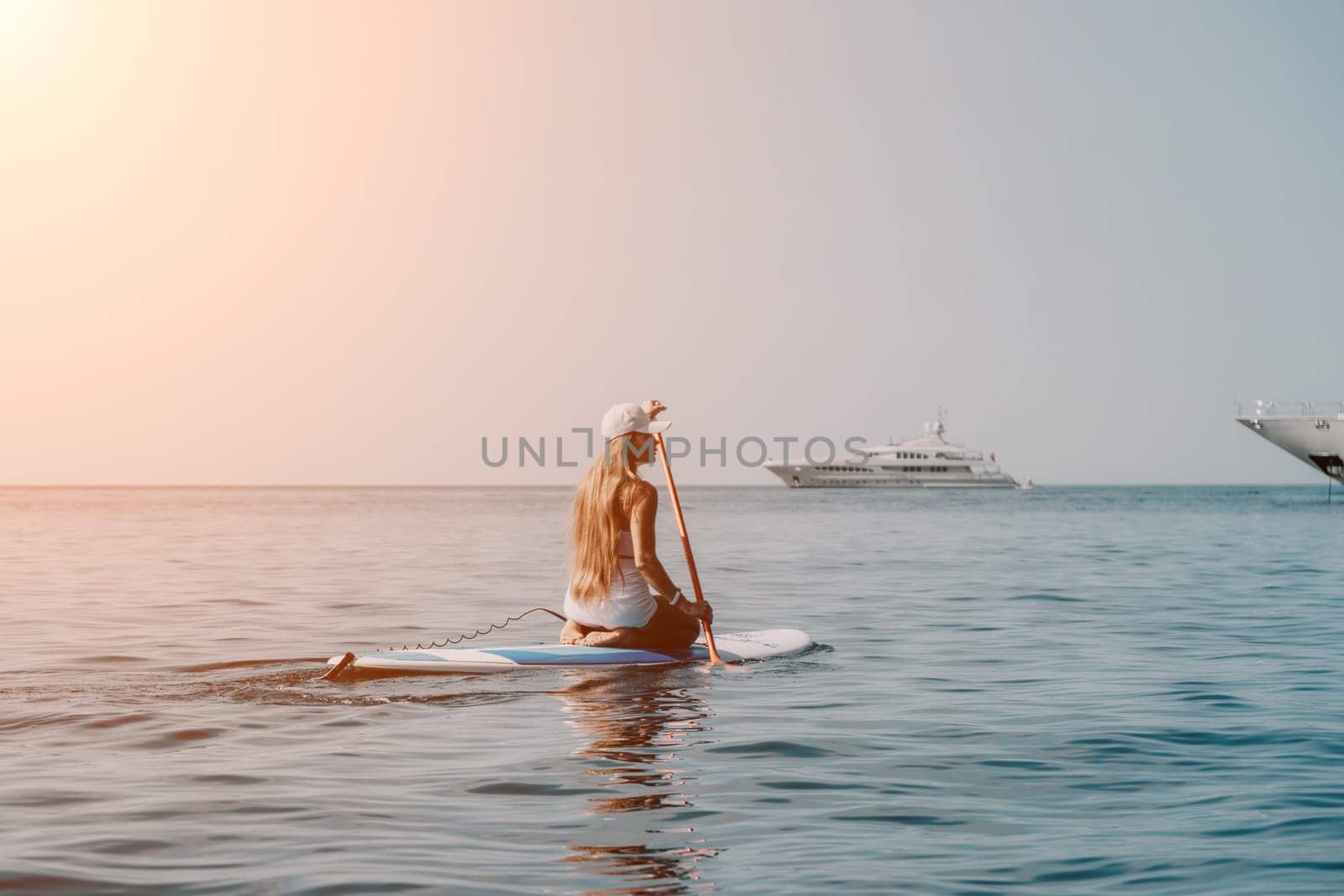 Close up shot of beautiful young caucasian woman with black hair and freckles looking at camera and smiling. Cute woman portrait in a pink bikini posing on a volcanic rock high above the sea