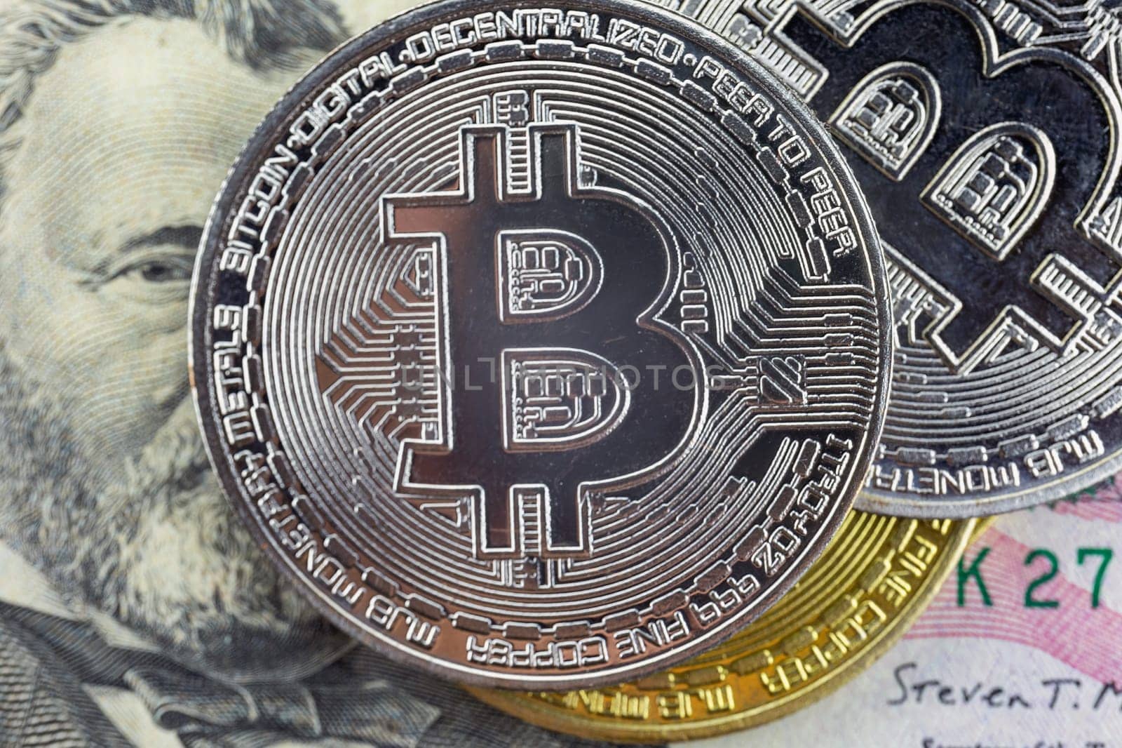 Bitcoin coins lie on a fifty dollar bill, close-up