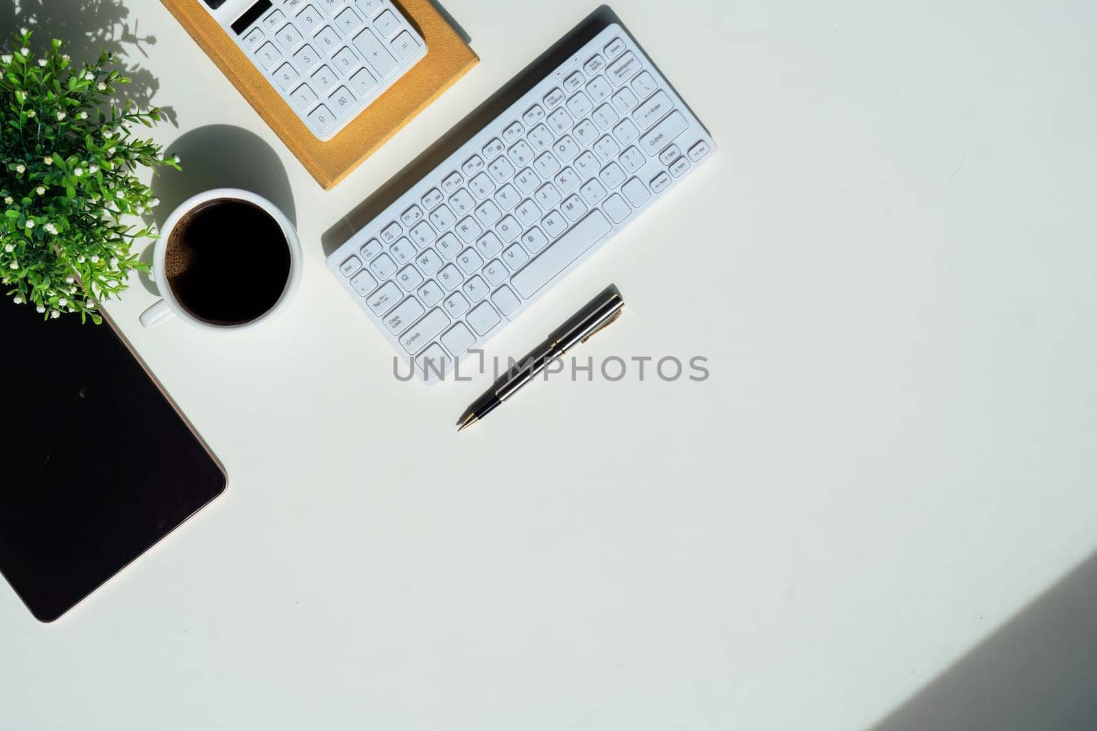 Top view above of white office desk table with keyboard computer, notebook and coffee cup with equipment other office supplies. business and finance concept. workplace, flat lay with blank copy space by nateemee