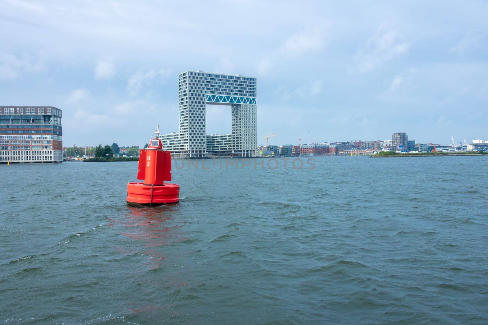 Netherlands. Summer day in Amsterdam. Buoy on the Amstel River and an office building on the bank