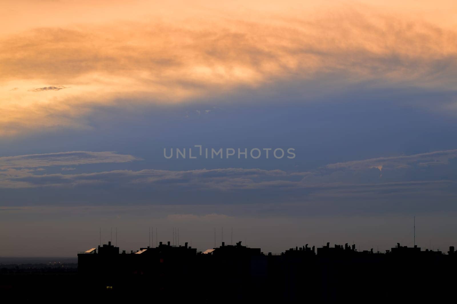Setting sun illuminated the clouds high in the sky above the city rooftops