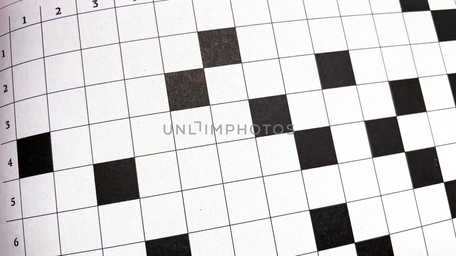 Mind Games.The Crossword Challenge.A close-up view of a crossword puzzle highlighting the intricate pattern of numbered squares and black blocks. Perfect for depicting the theme of problem-solving, leisure activities, or intellectual pursuits.