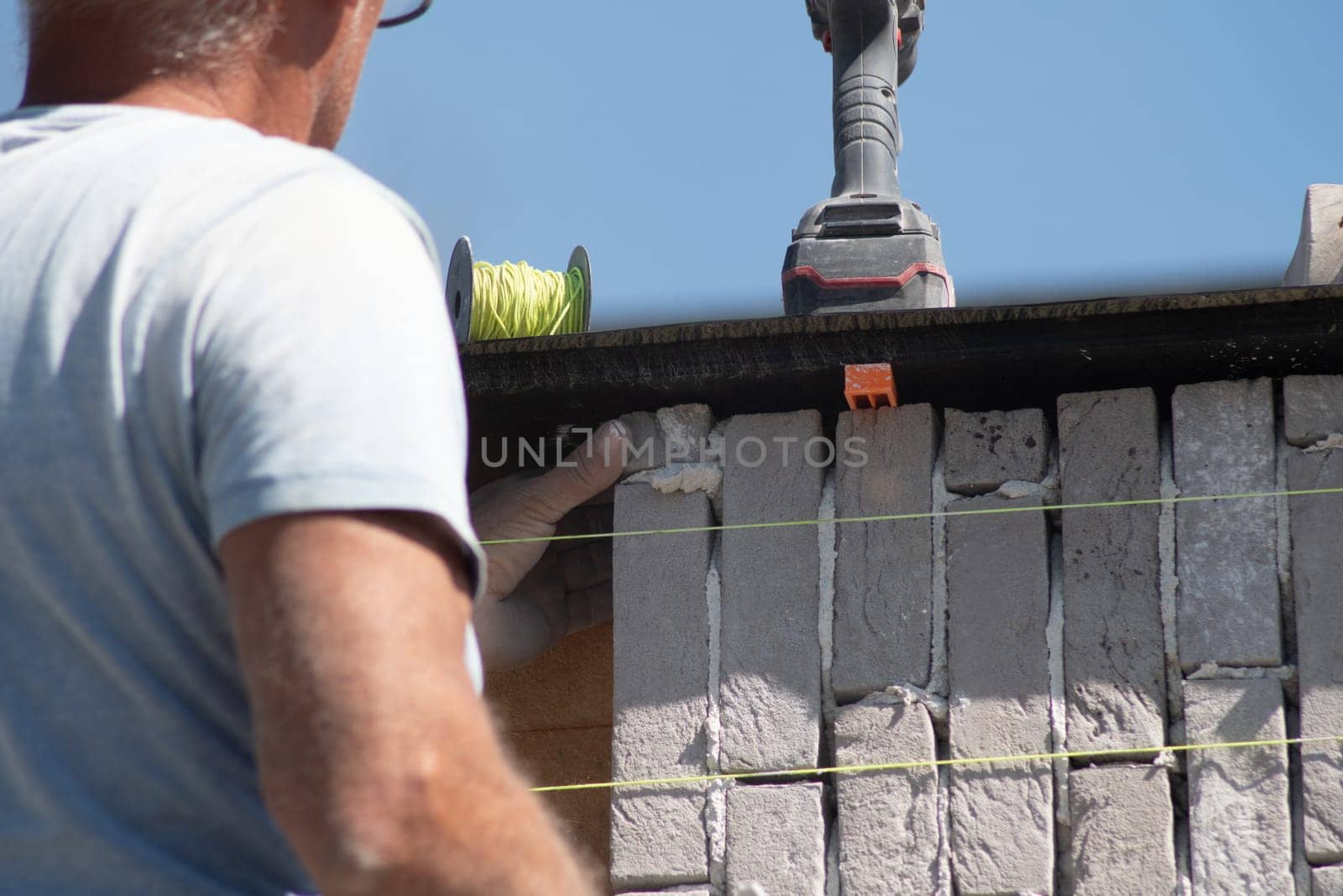 Builder aligning bricks on wall with level, tools in background, Concept of precision in construction work,