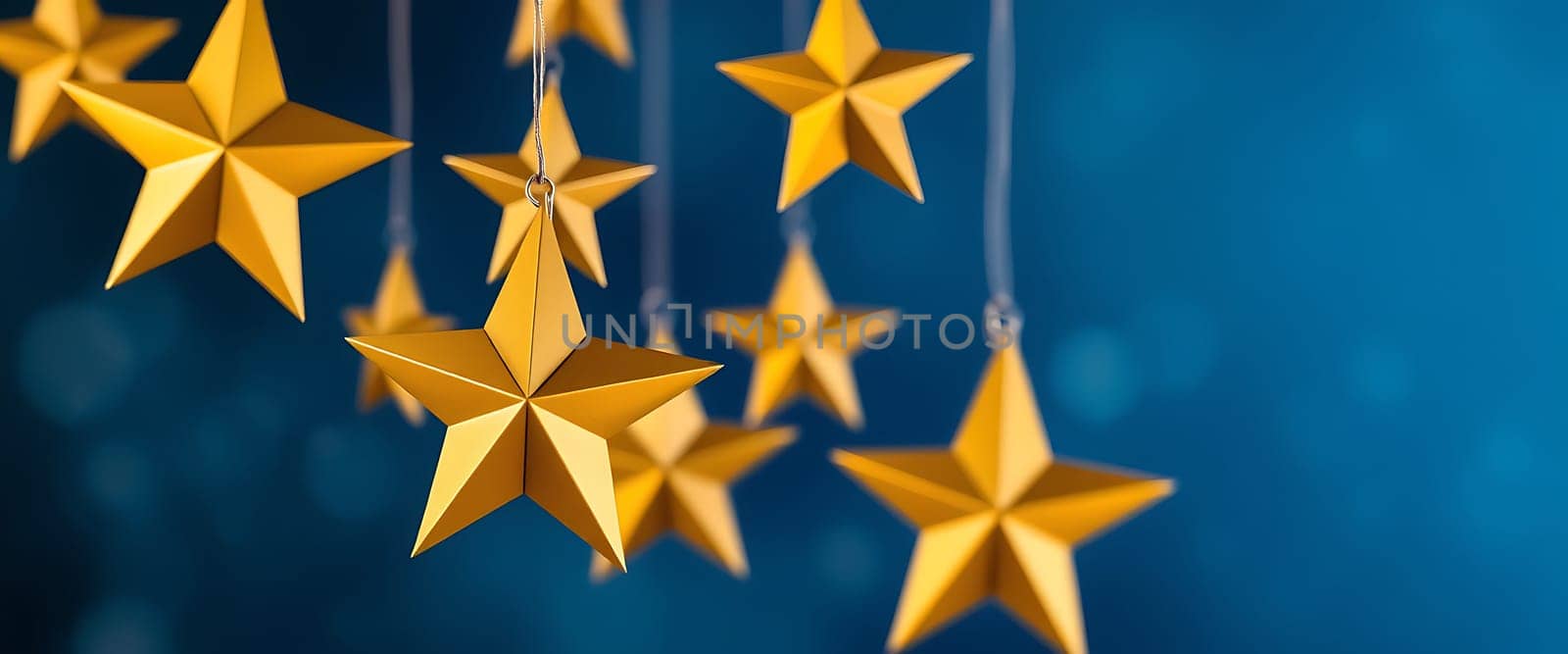 Bright golden stars dangle from thin strings, creating a whimsical and festive display against a deep blue background, perfect for celebrating special occasions.