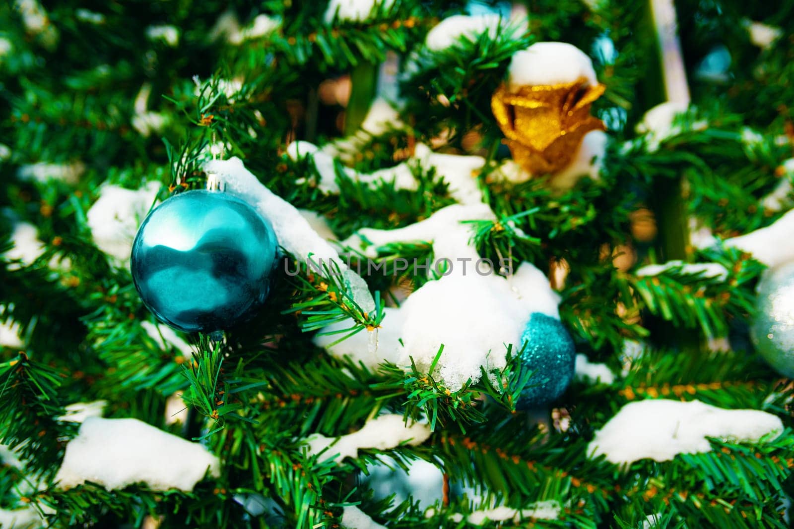 Decorated Christmas tree. Close-up of blue and gold balls with snow hanging from a decorated Christmas tree.