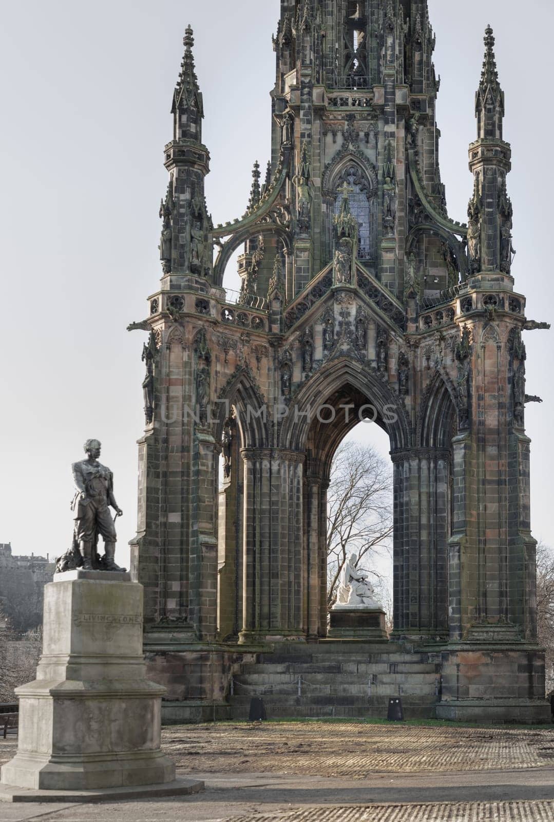 Edinburgh, Scotland - Jan 16, 2024 - The statue of Explorer David Livingstone in front of The Scott Monument is a Victorian Gothic monument in Princes Street Gardens at the city of Edinburgh. Space for text, Selective focus.