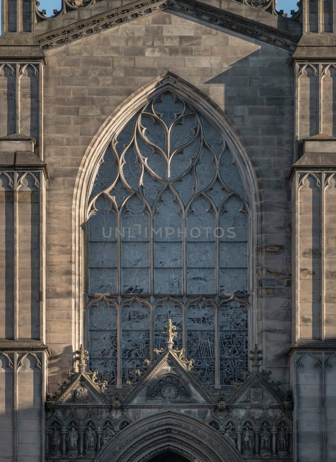 Edinburgh, Scotland - Jan 18, 2024 - The Sun shines through the surface of Stained Glass Arched Windows and The Gable is above the entrance door of St. Giles’s Cathedral in Edinburgh. Exterior architectural detail of the High Kirk in Neo-gothic. Religious architecture, Space for text, Selective focus.