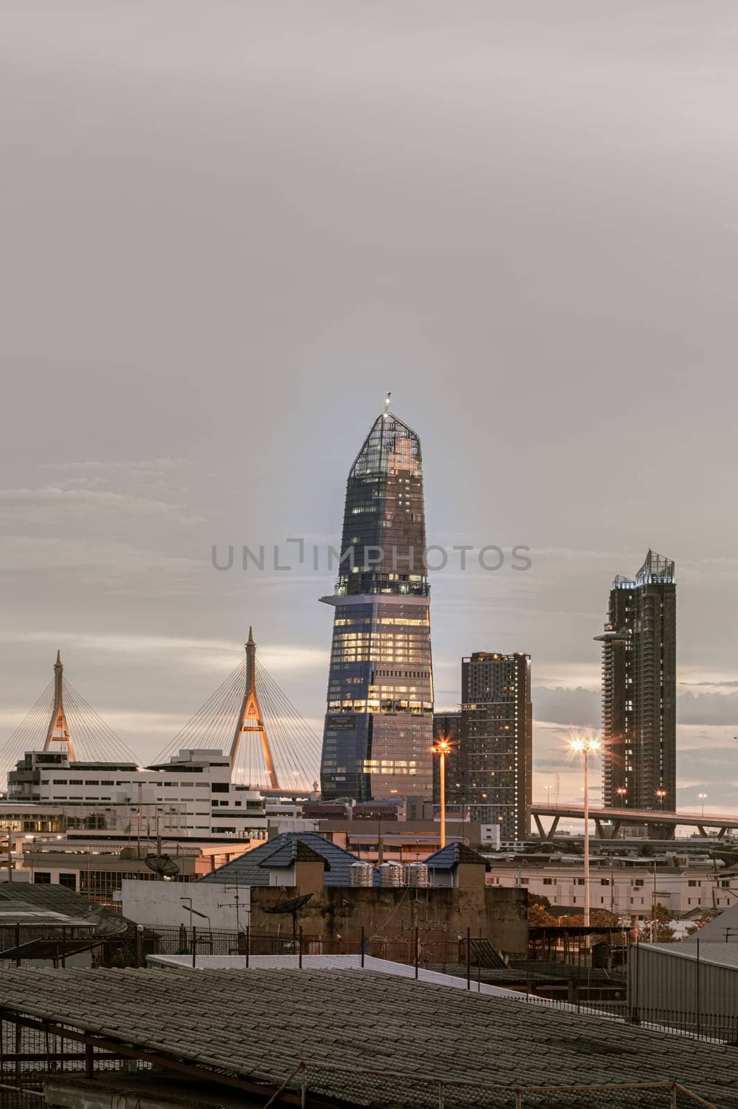 Bangkok, Thailand - Aug 14, 2024 - City view with KingBridge tower alongside the iconic landmark of Bhumibol Bridge. Stunning At Twilight skyline of bangkok business district with Skyscrapers use it as your wallpaper, poster and banner design, Selective focus.