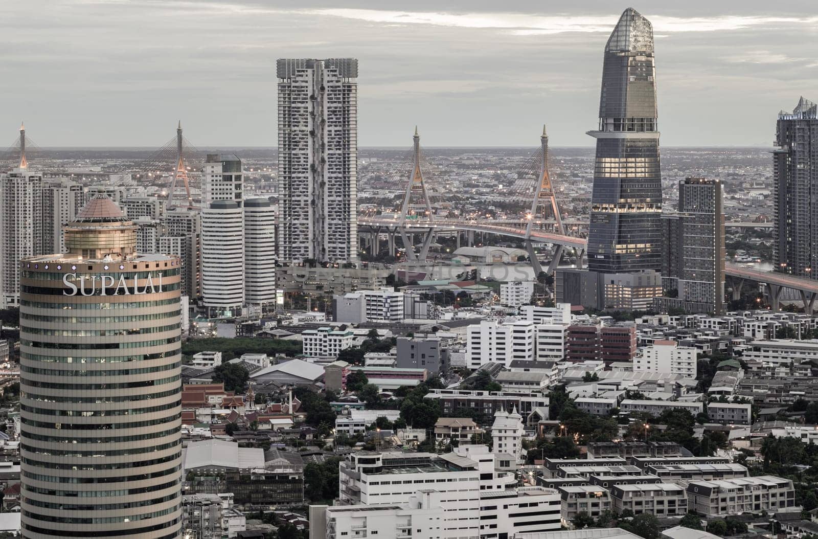 Bangkok, Thailand - 29 Aug, 2024 - Aerial view of KingBridge tower, Supalai Grand Tower alongside the iconic landmark of Bhumibol Bridge, Stunning At skyline of bangkok business district with Skyscrapers use it as your wallpaper, poster and banner design, Selective focus.