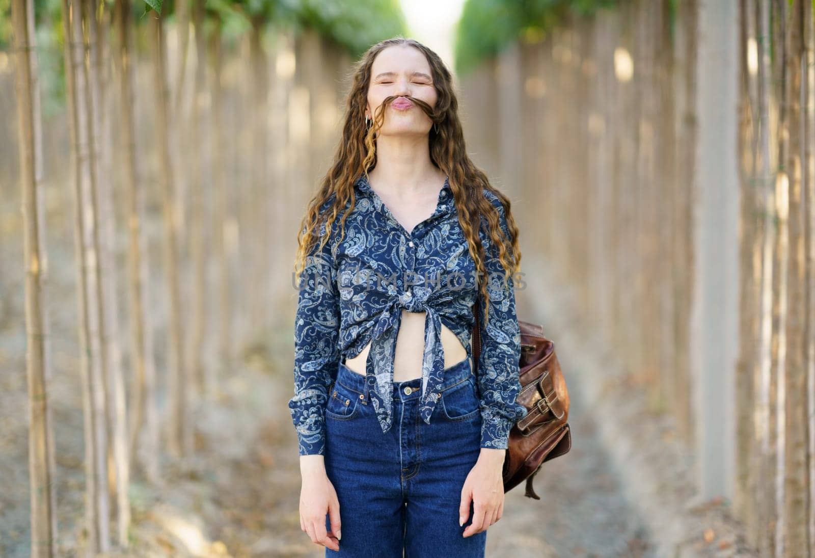 A playful and vibrant young woman poses confidently on a beautiful scenic pathway, showcasing her unique and trendy fashion sense while exuding her joyful and freespirited personality