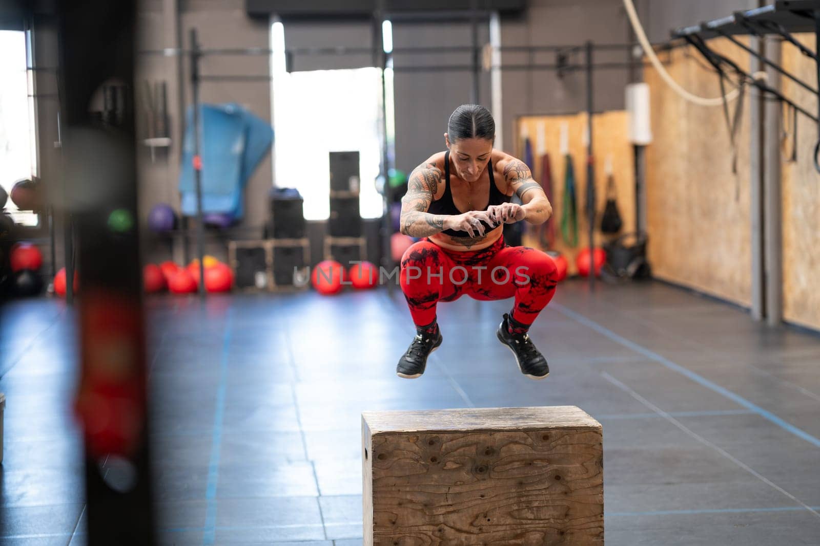 Strong mature woman exercising jumping on a box in a gym
