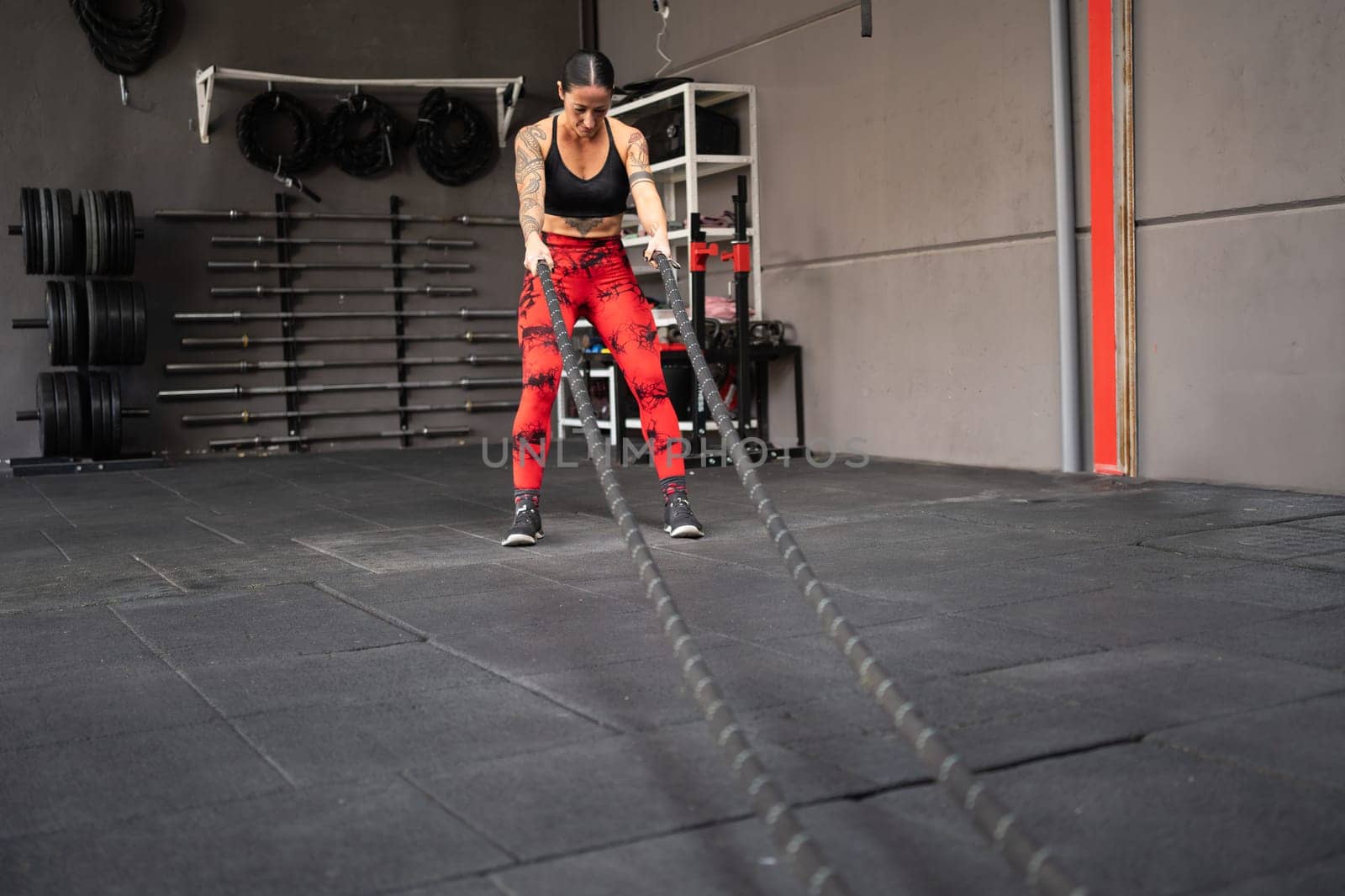 Photo with copy space of a strong woman using battle rope in a gym