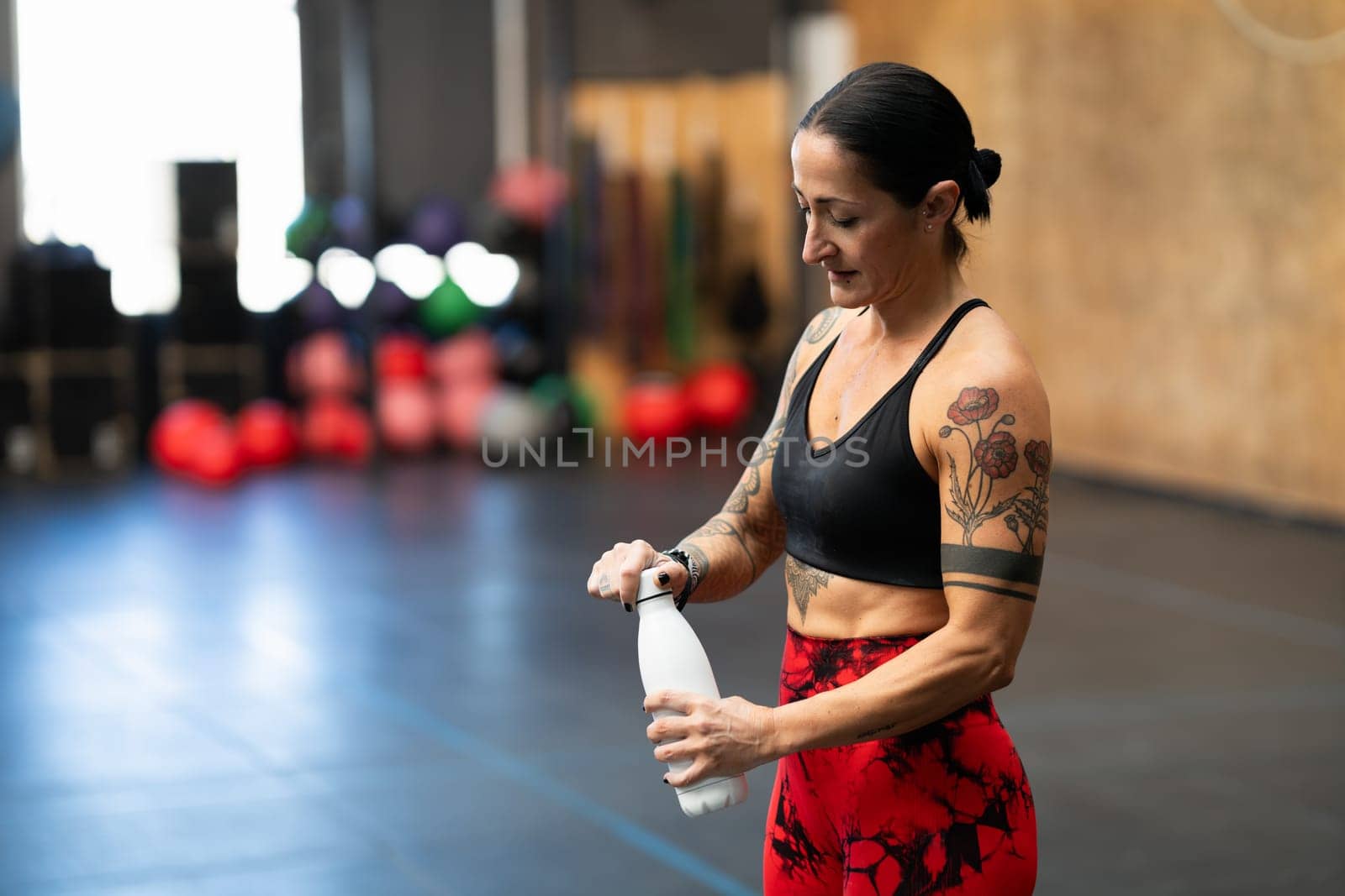 Mature sportive woman about to drink water after training in gym