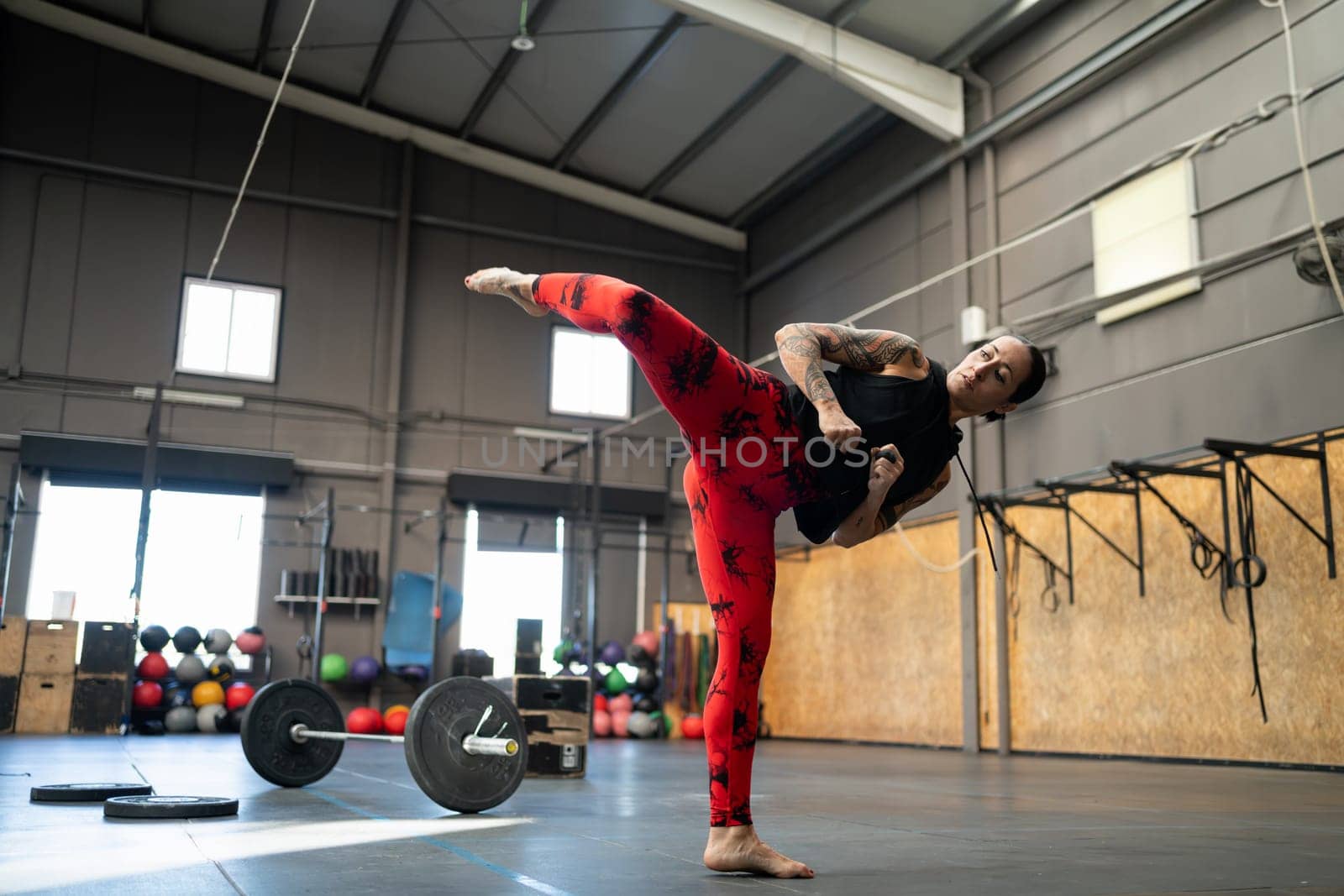 Sportive strong woman throwing a kick in the air in the gym