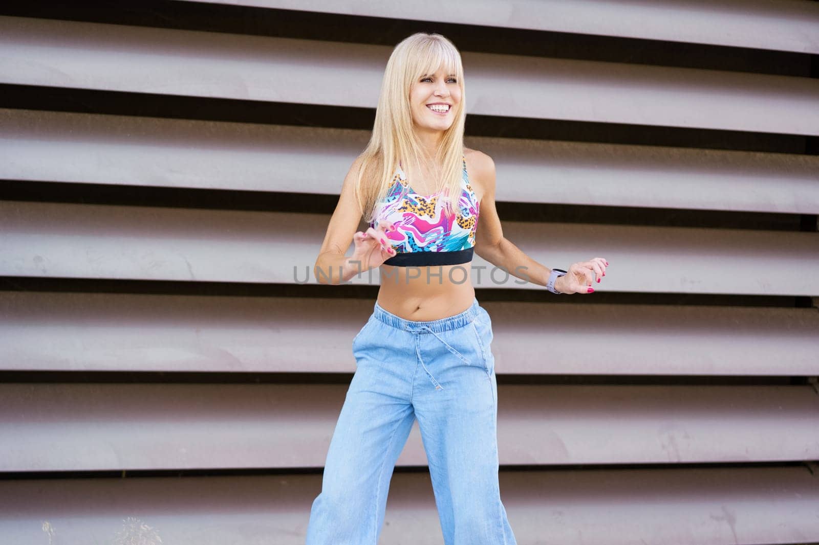 Happy blonde female beauty dancer performing choreography in the city