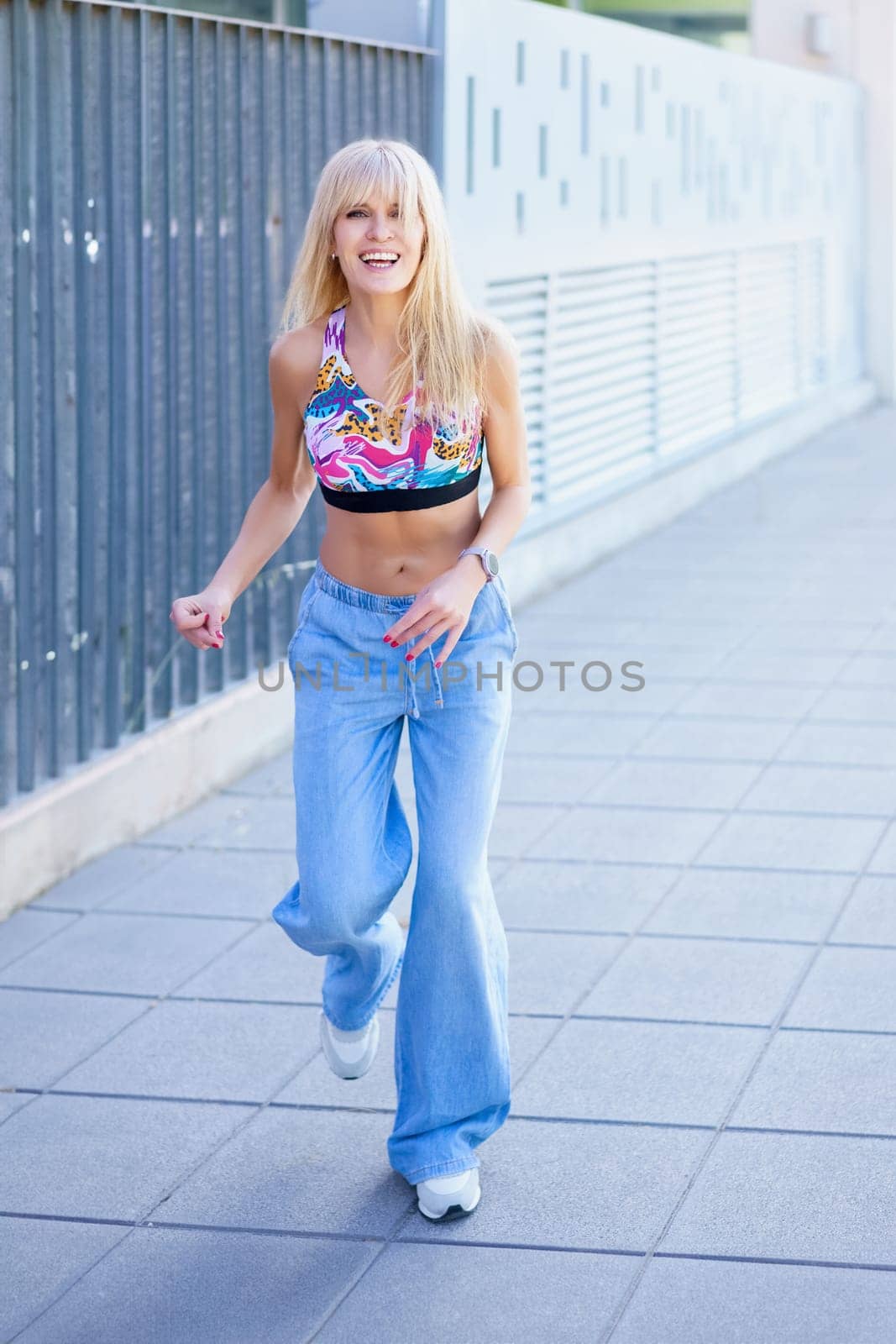 Vertical full length photo of a happy woman dancing and laughing in the street