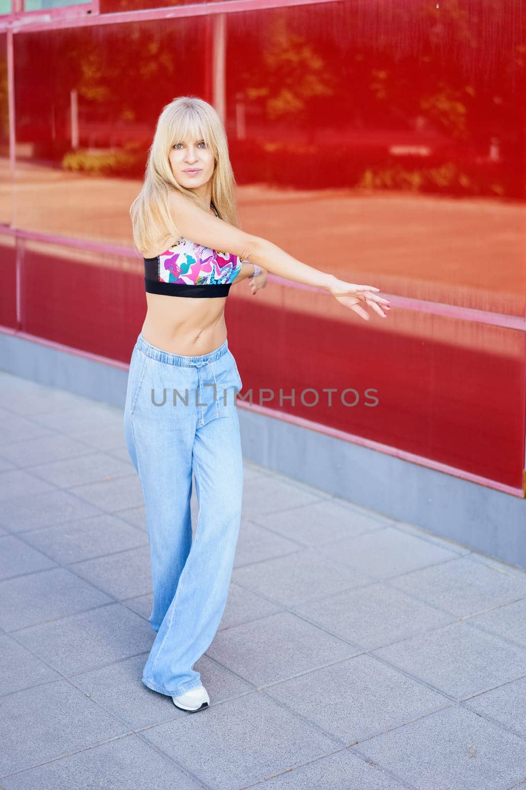 Vertical full length photo of a cool casual blonde beauty caucasian woman dancing free style in the city