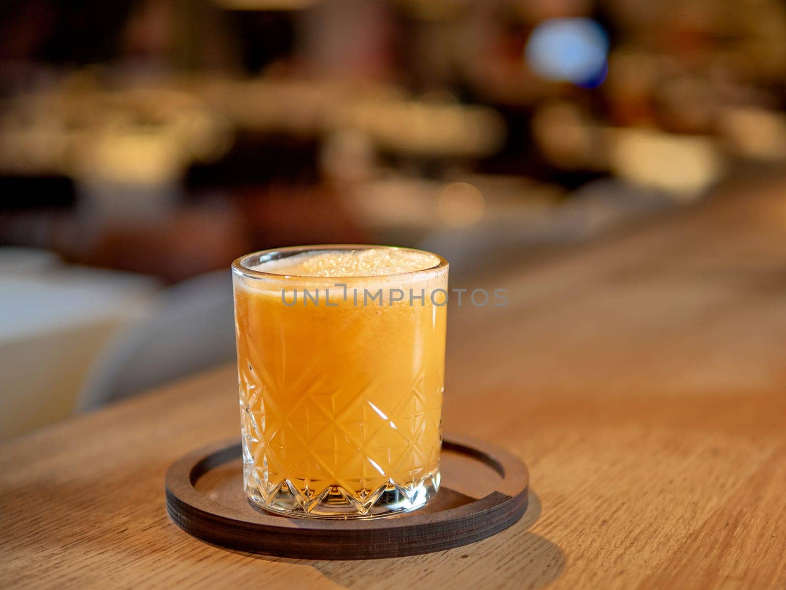 Glass of fresh orange juice on bar counter in restaurant interior. Delicious cold orange fresh juice or cocktail in bar or nightclub. Copy space