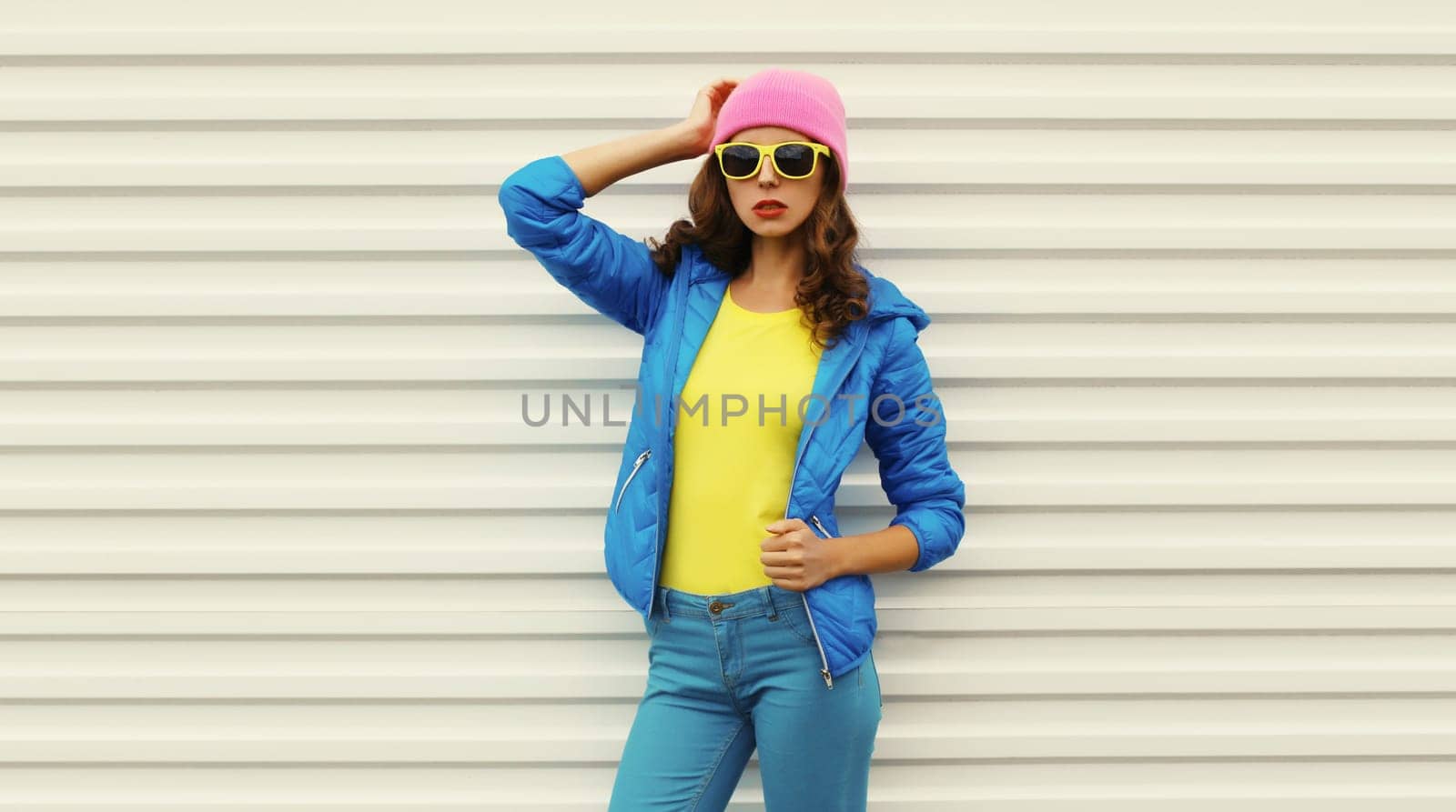 Stylish modern young woman in vivid colorful clothing, pink hat, blue jacket, fashion teenage girl posing on white background